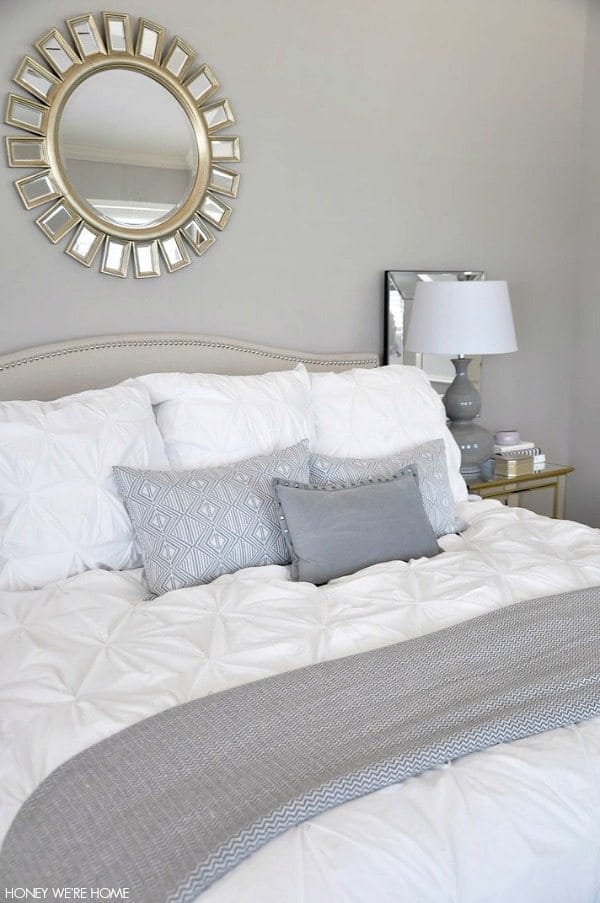 neutral master bedroom, white bedding, gray pillows and accents, sunshine mirror
