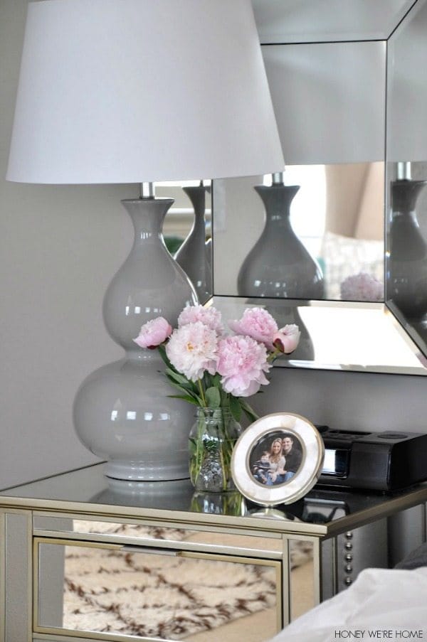 neutral master bedroom, mirrored nightstand and gray lamp