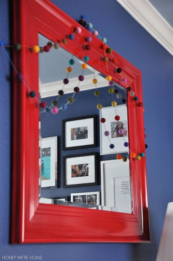 Spray painted mirror with colorful felt ball garland is fun in a kid's room