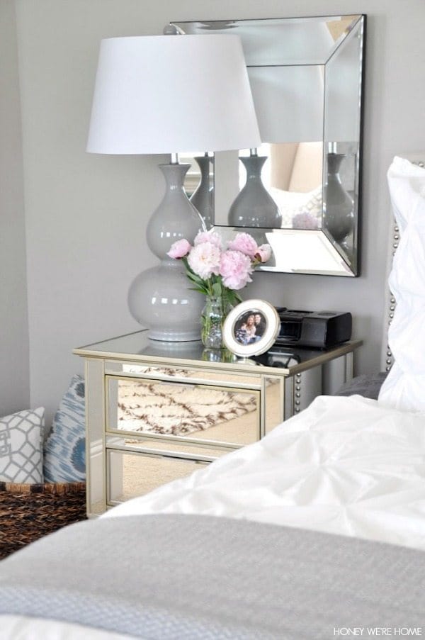 neutral master bedroom, white and gray bedding mirrors, lamp, night stand and pillows