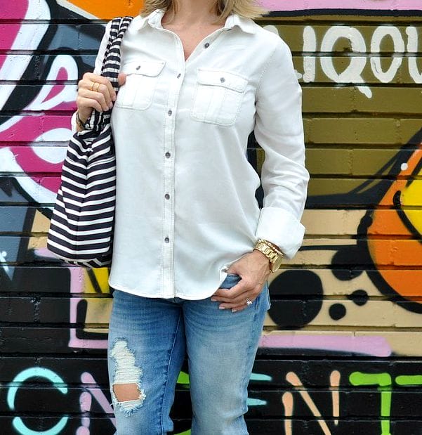 Fall fashion - distressed jeans and white button down with striped bag