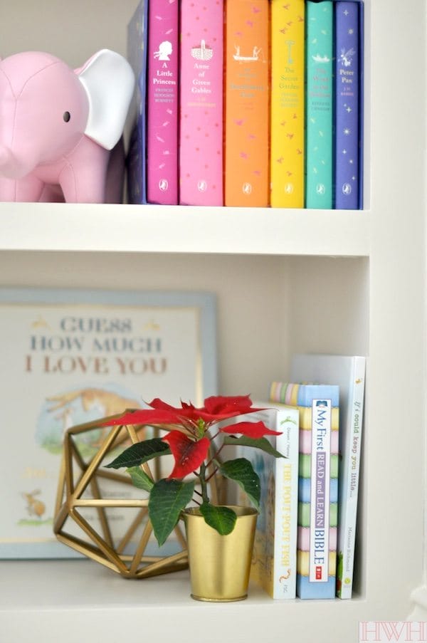 Festive holiday nursery bookshelf with pink and gold decorations. | Honey We're Home