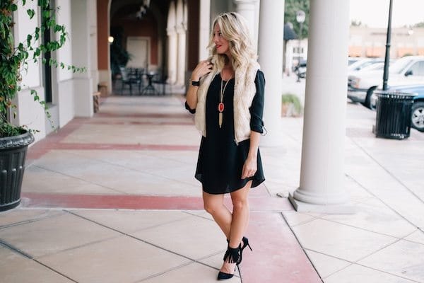 Fall fashion - little black dress with red Kendra Scott necklace and fringe heels + faux fur vest