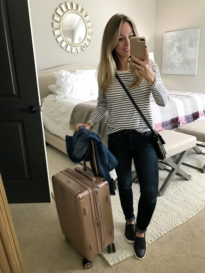 Fall fashion comfy travel outfit - striped top, jeans and slip on sneakers with rose gold luggage