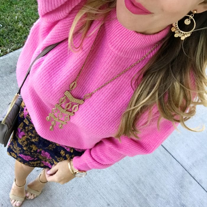 pink sweater with brocade skirt and gold accessories